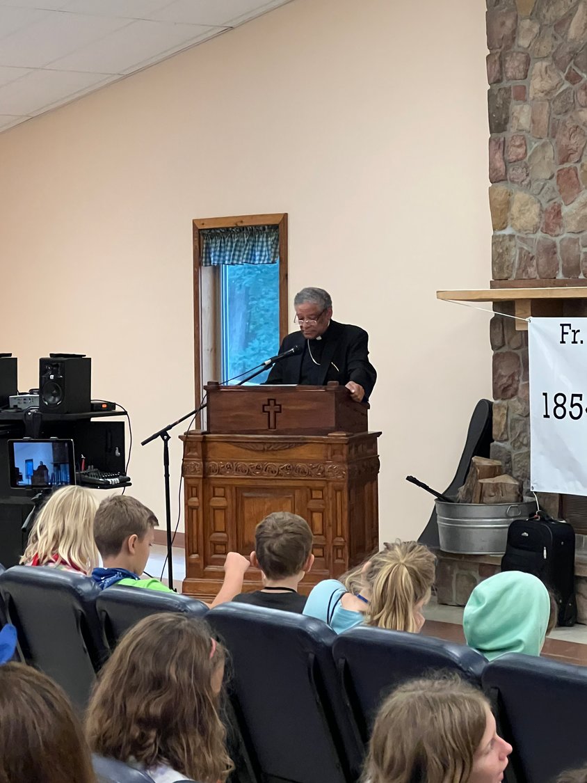 Auxiliary Bishop Joseph N. Perry of Chicago, postulator for the sainthood cause of Venerable Father Augustus Tolton, speaks to children about the life of Venerable Father Augustus Tolton during Camp Tolton at Camp Jo’Ota in Clarence.